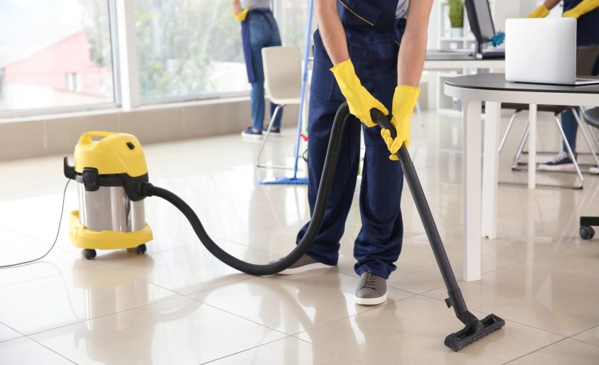 Janitor hoovering floor in office